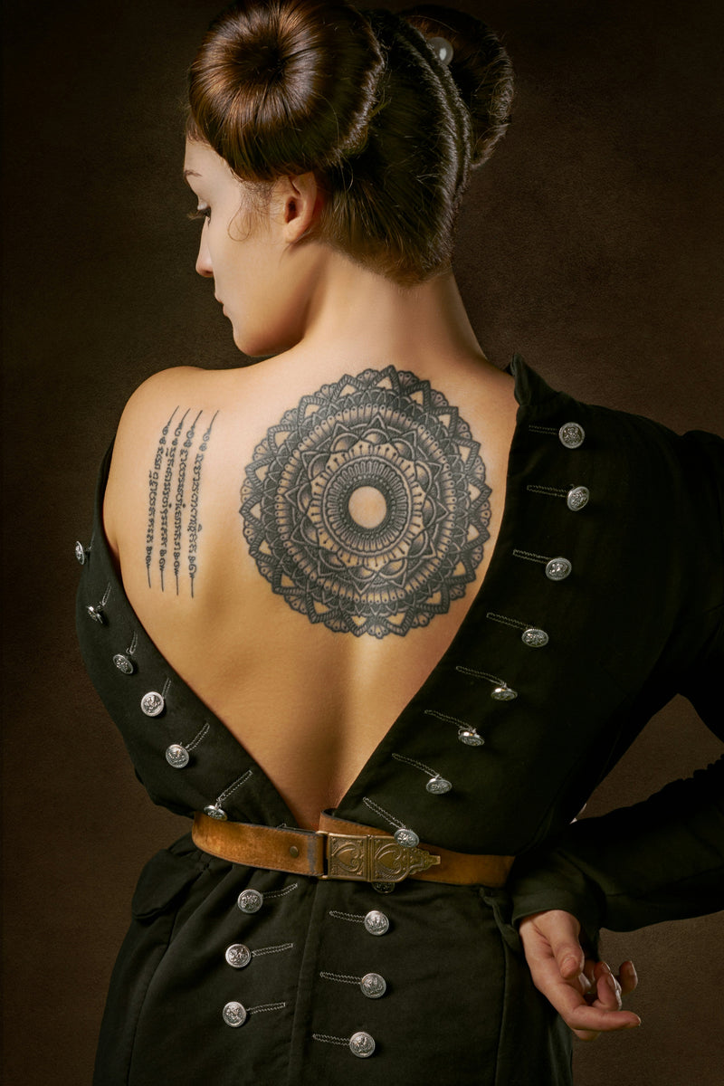 A large mandala tattoo across a woman's back, the kind of dense piece often lightened for a cover-up.