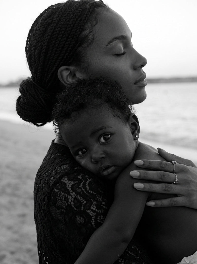 Black-and-white image of a mother holding her child close by the sea.
