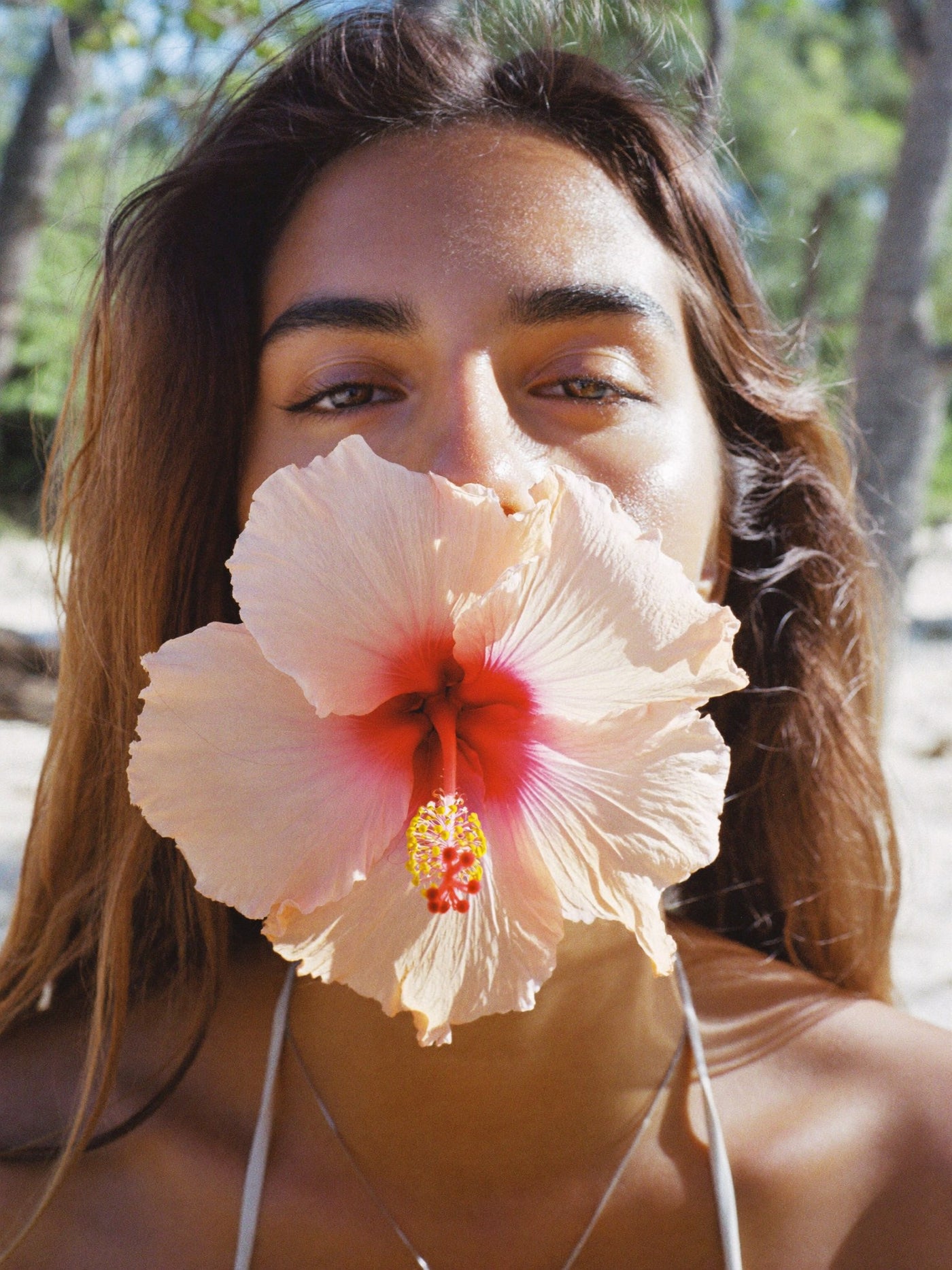 Woman holding a hibiscus flower over her lower face, Acne Treatment Packages at Pink Laser Clinics