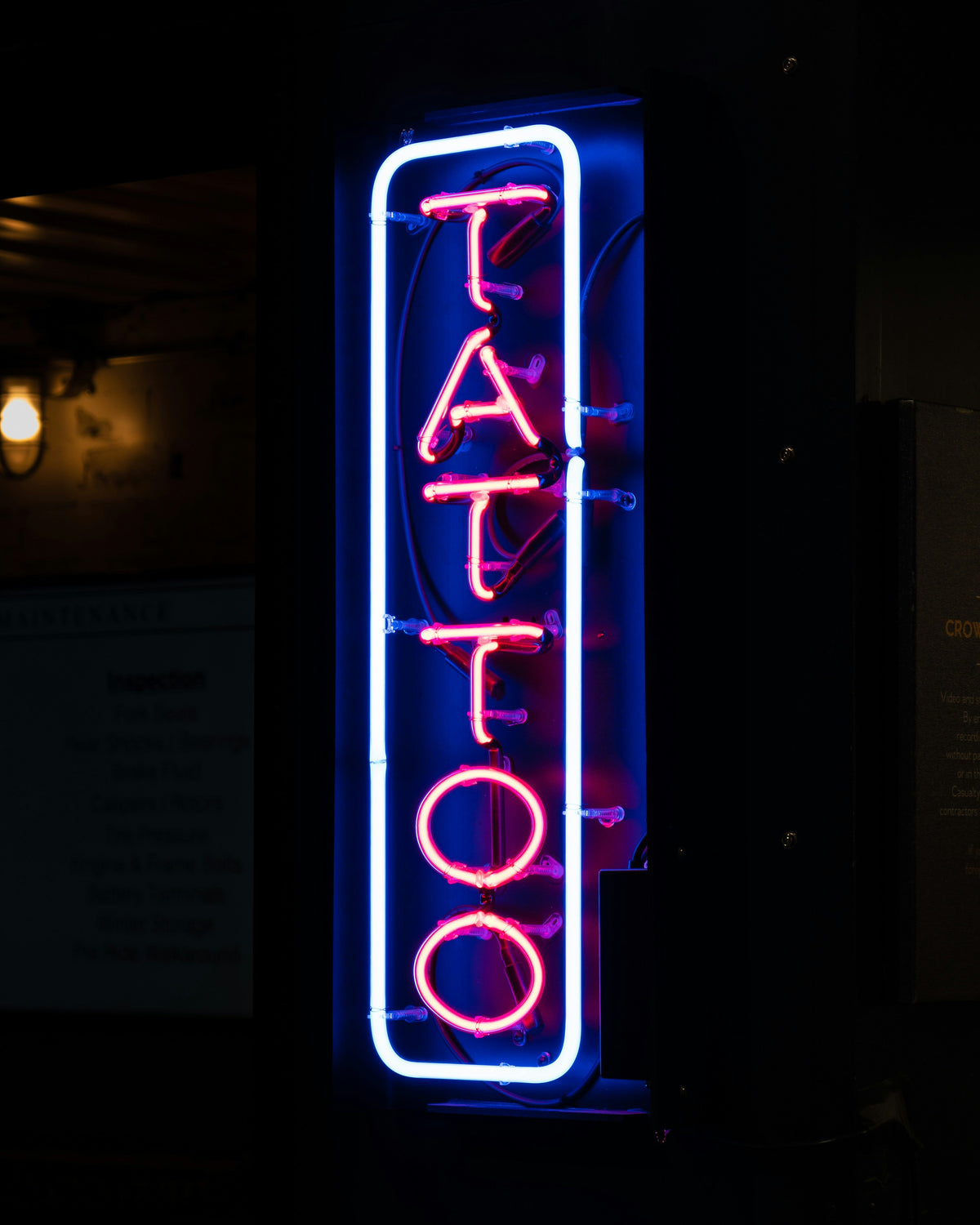 A glowing neon 'Tattoo' sign. The cost difference between applying a tattoo and removing one can be significant.