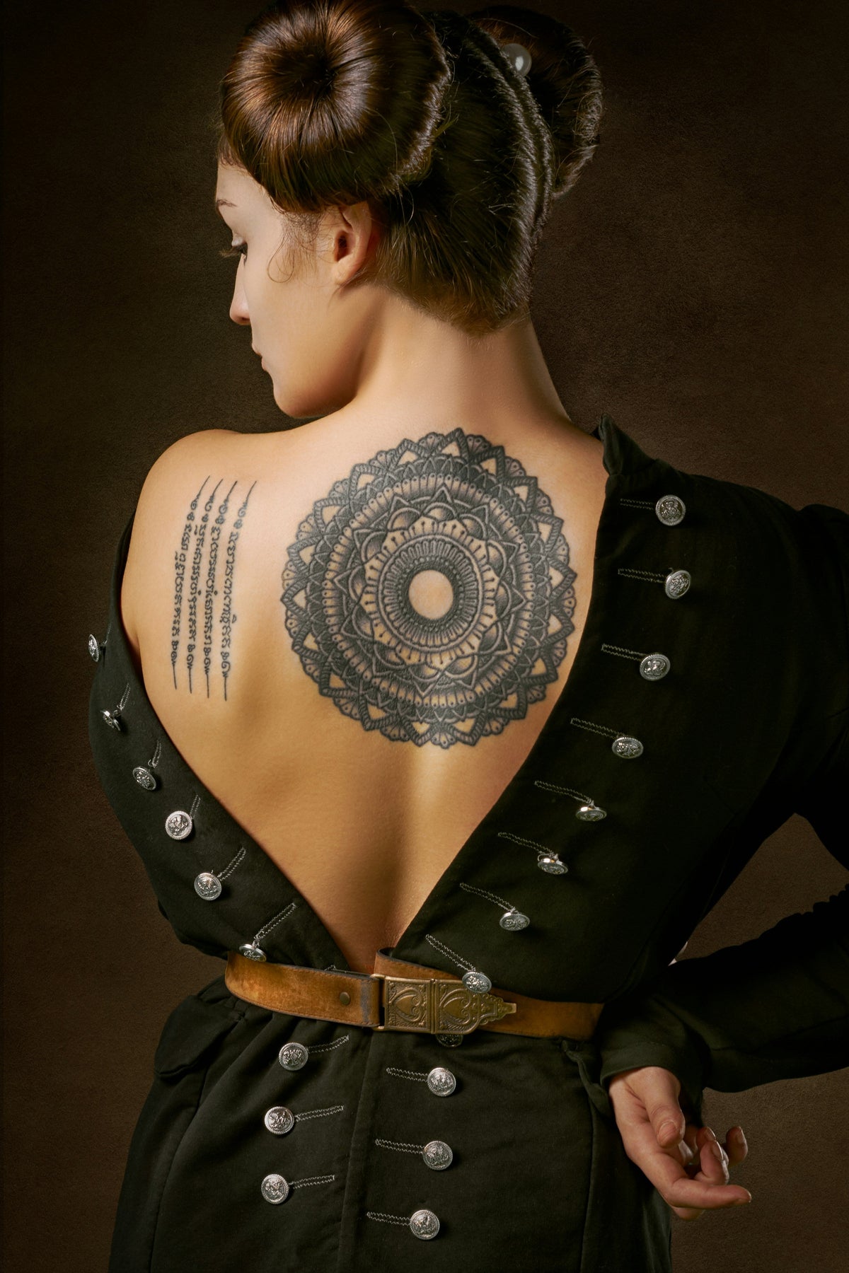 A large mandala tattoo across a woman's back, the kind of dense piece often lightened for a cover-up.