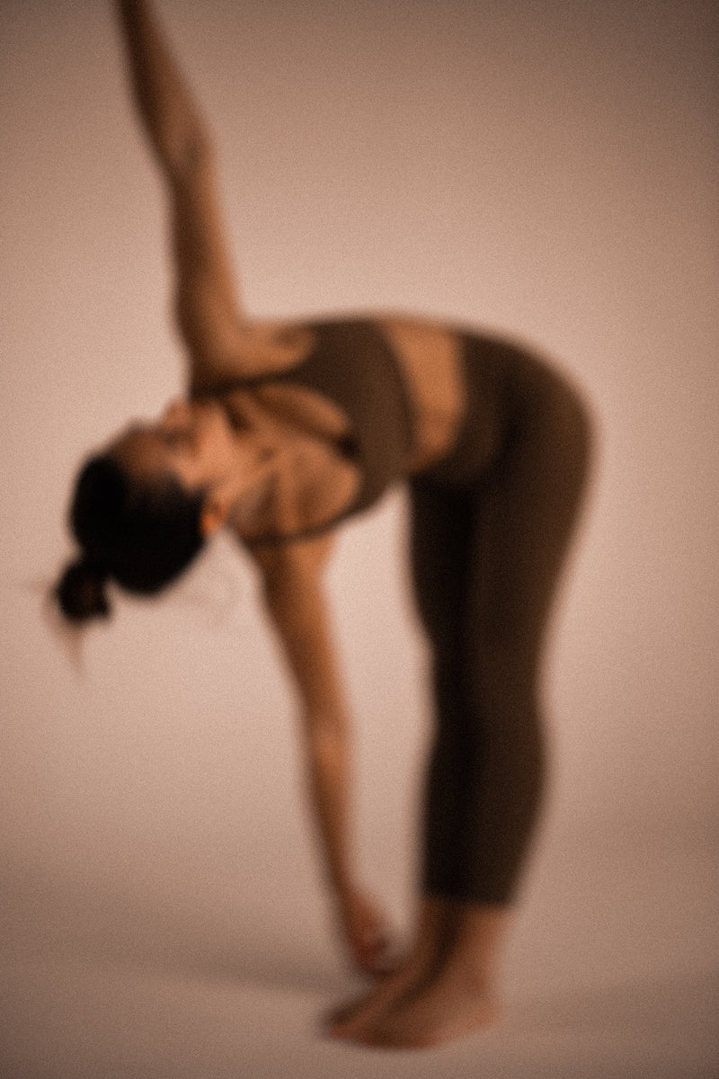 Woman in warm-toned activewear in a standing side stretch, highlighting core strength and posture.