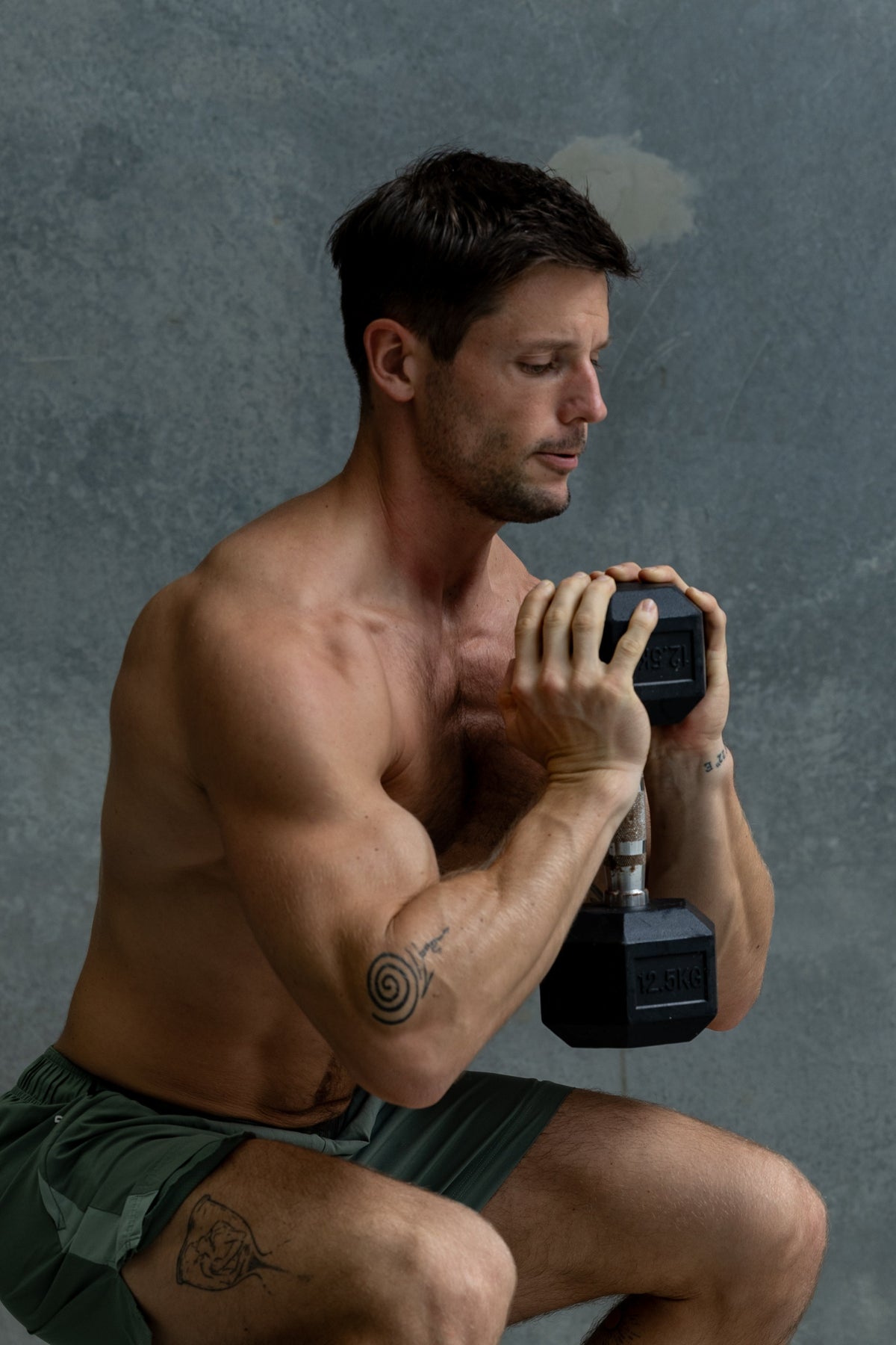 Fit, shirtless man crouching while holding a kettlebell during strength training.