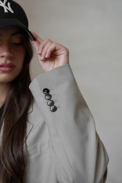 Woman in a cream blazer and black cap, minimal portrait