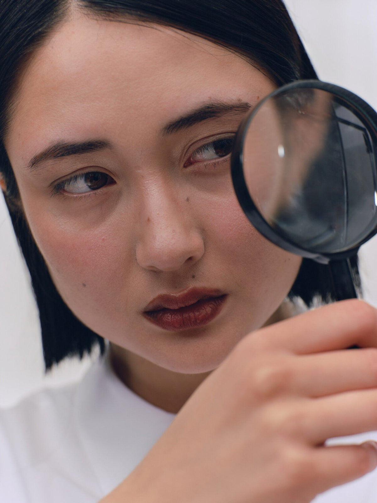 Looking closely through a magnifying glass, telling a skin tag, mole and seborrhoeic keratosis apart.