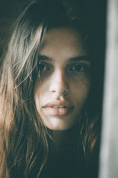 Natural-light editorial portrait of a woman with clear, lightly freckled skin and a calm, direct gaze.