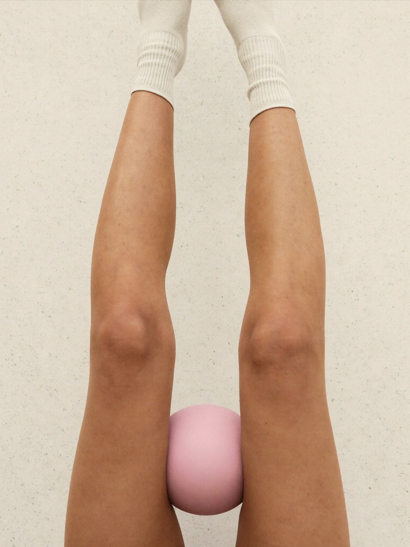 Raised legs with a pink ball held between the knees, Dark Knees Treatment Package at Pink Laser Clinics